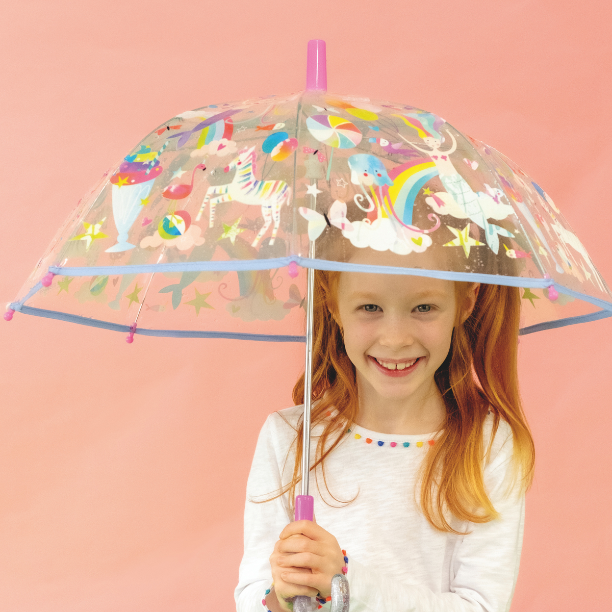 a girl holding A transparent children's umbrella with colorful animal and fantasy character illustrations, featuring a rainbow, mermaids, and other elements.