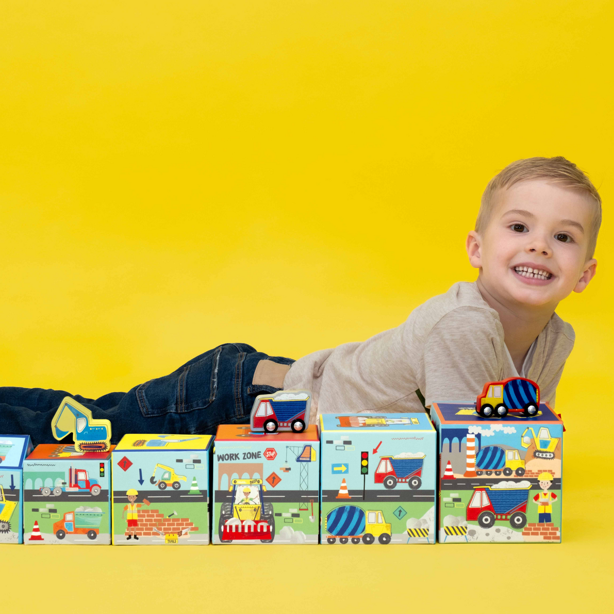 boy lying down next to the construction stack and play