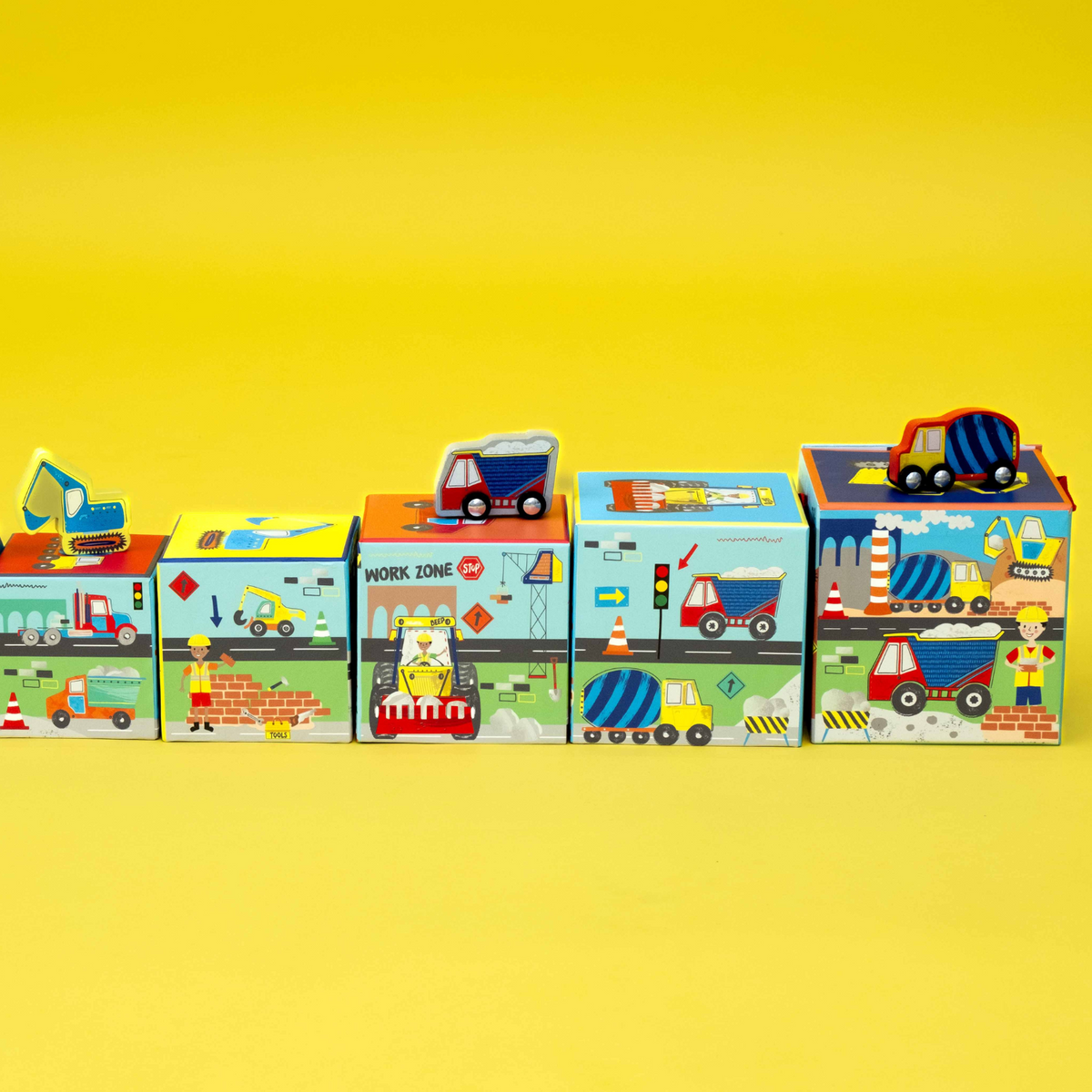 A colorful box with a carry handle, labeled 'Stack & Play', featuring images of construction vehicles like diggers and trucks.