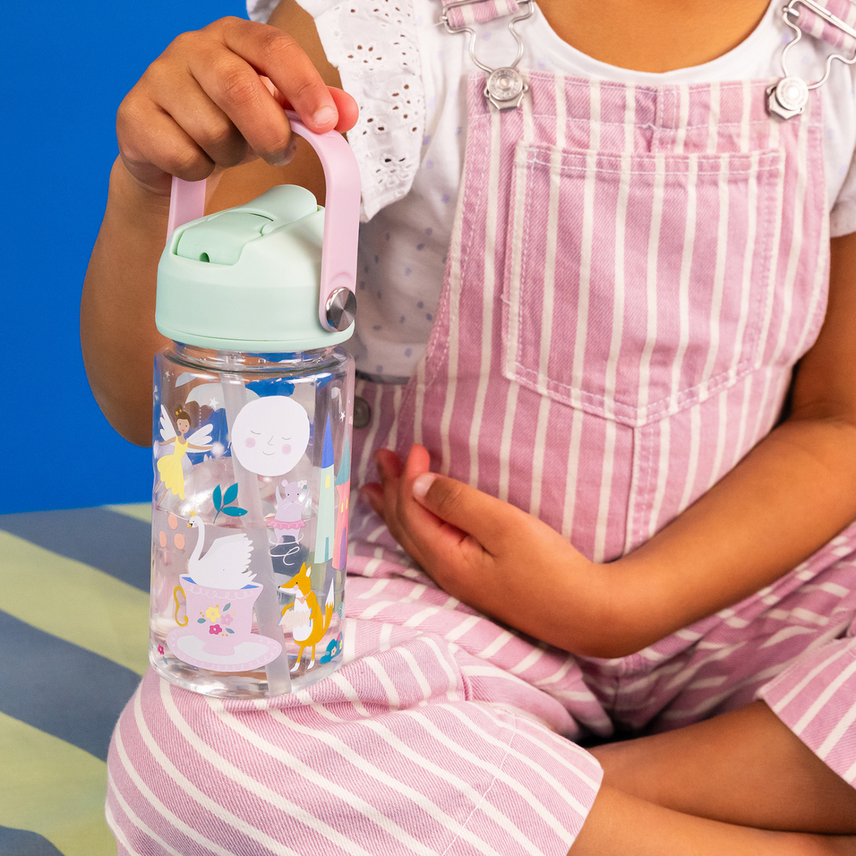 a girl holding A 450ml Tritan drinks bottle with a pastel green lid, pink carry handle, and illustrated with fairies in a floral setting.