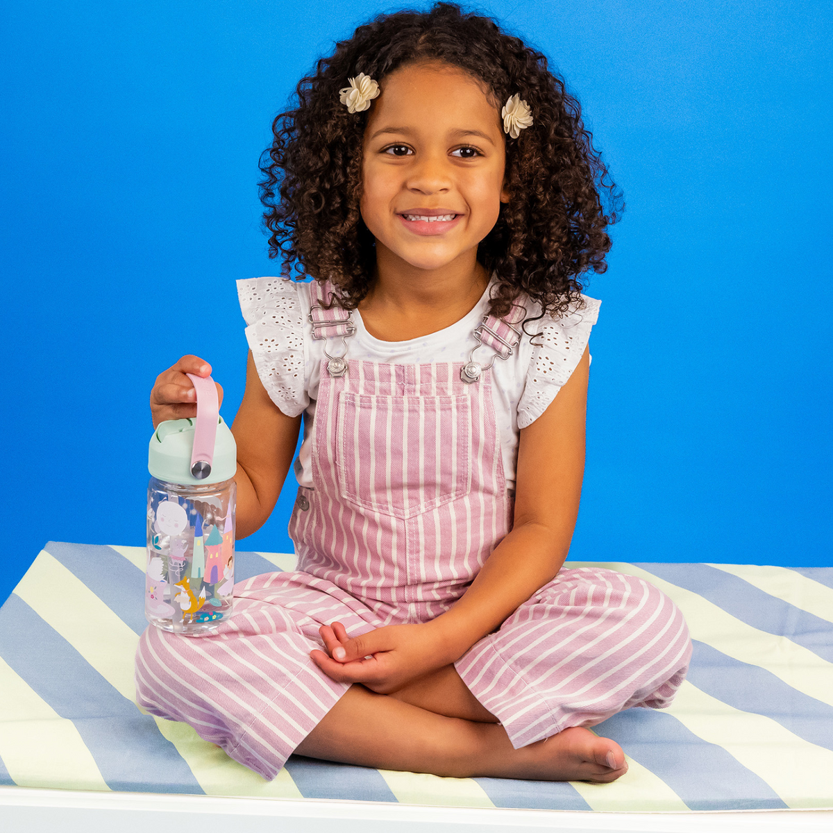 a girl holding A 450ml Tritan drinks bottle with a pastel green lid, pink carry handle, and illustrated with fairies in a floral setting.
