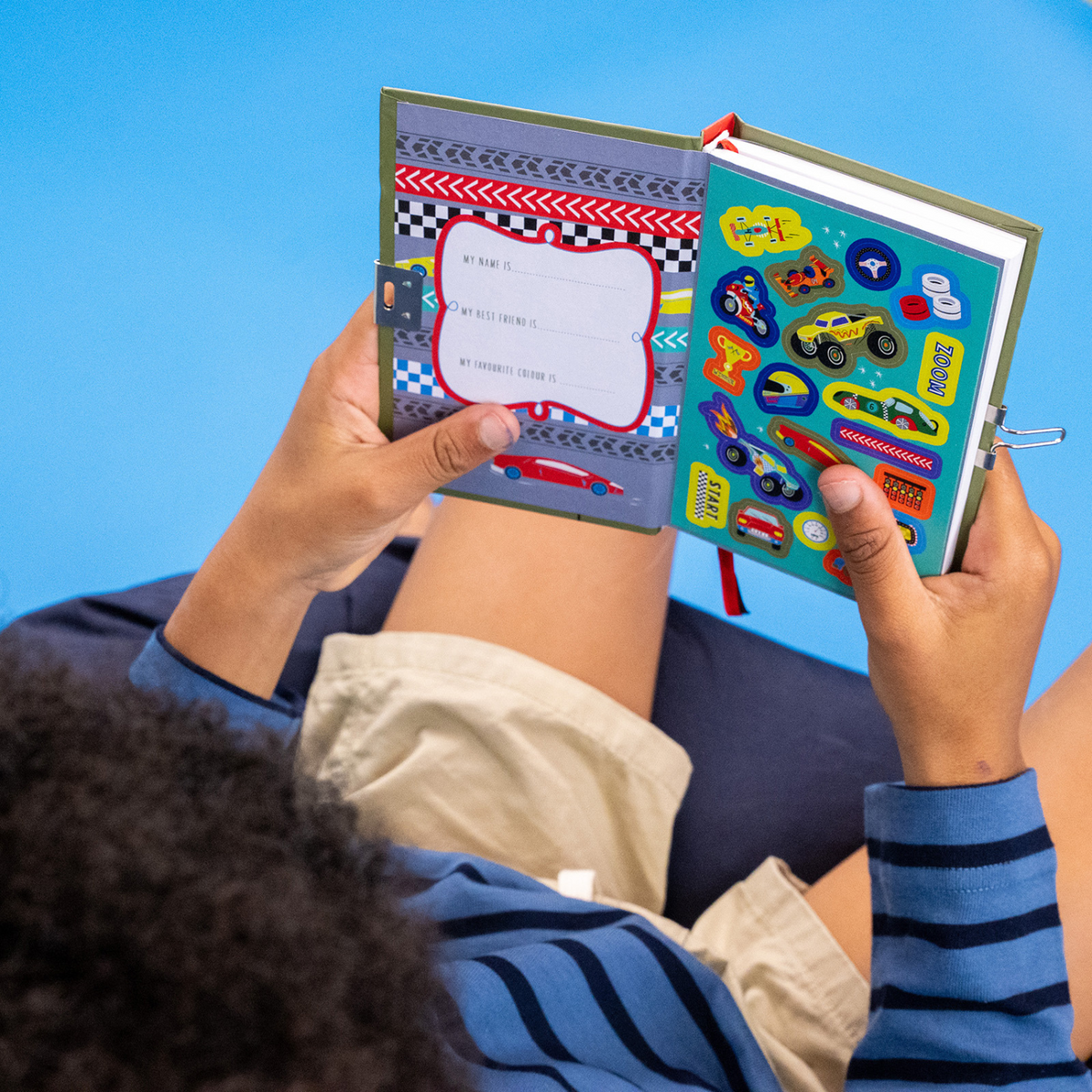 a boy sitting holding the cars diary