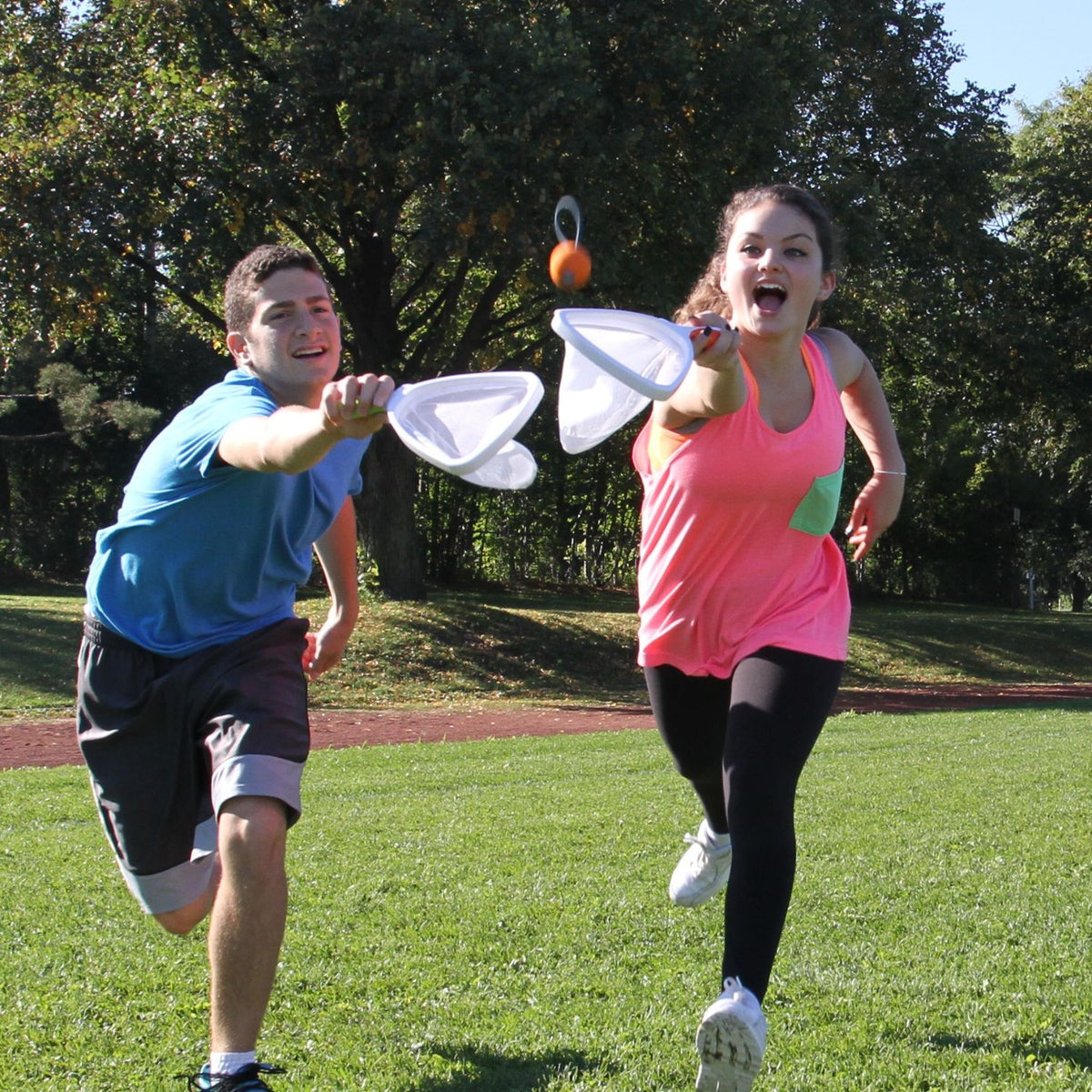 Two teenagers standing far apart on a wide green lawn, launching and catching the loop balls in a fast-paced head-to-head match.