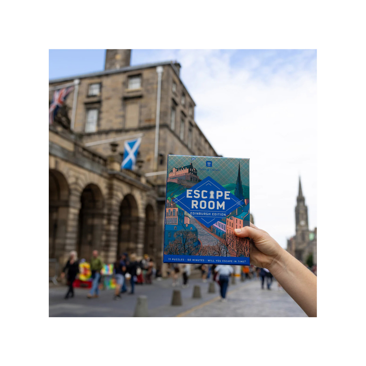 Hand holding an 'Escape Room' book with a cityscape background