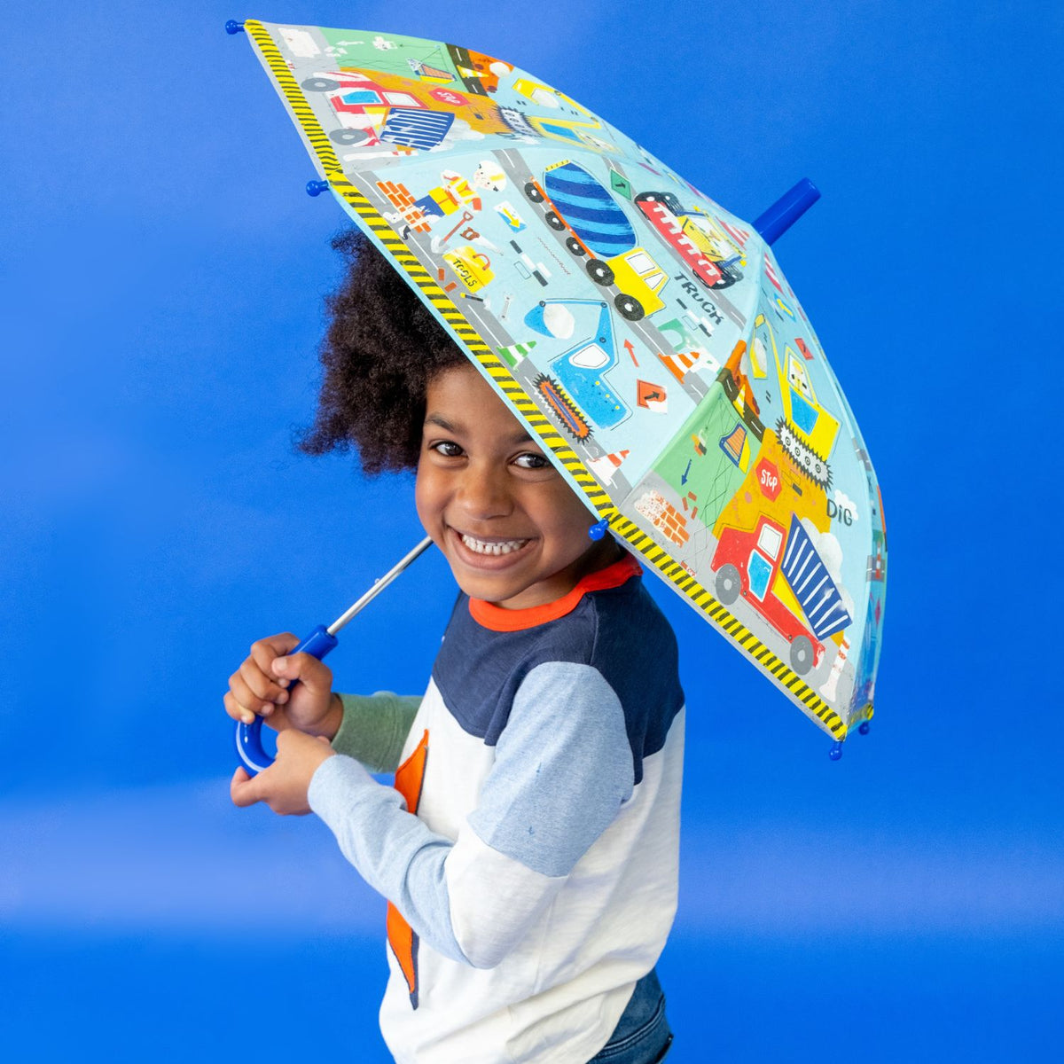 Child holding a colorful umbrella with construction design 