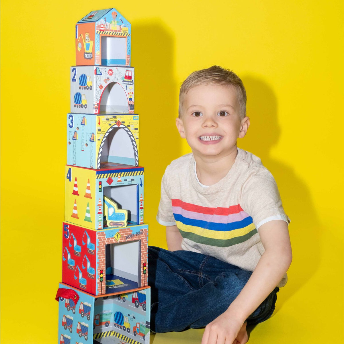 Child with a colorful stack of construction themed toy stacking blocks 