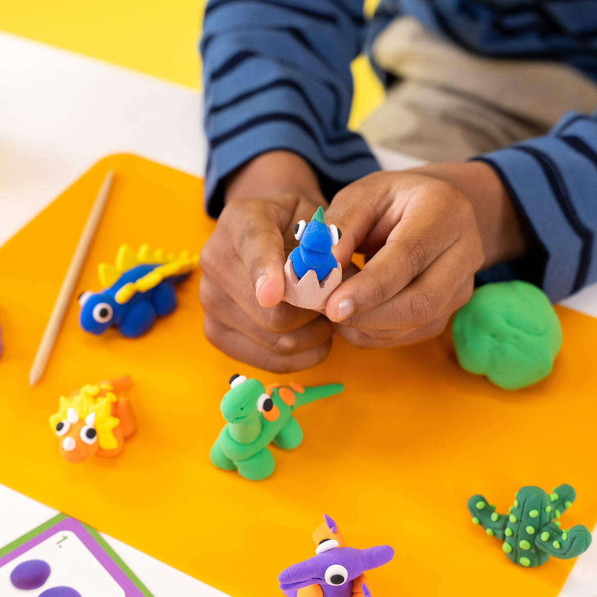 a close up of a boy holding one of dinosaur air dry clay and play creations 