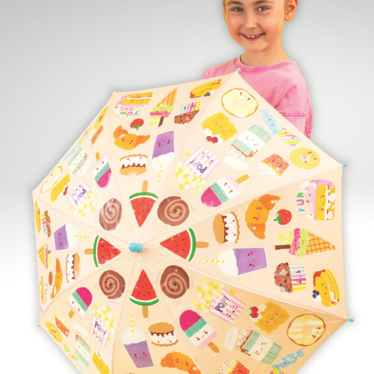 Child holding a colorful umbrella with food-themed patterns