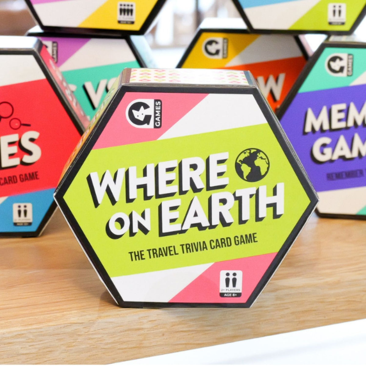 Hexagonal 'Where on Earth' card game box with colorful game boxes in the background.