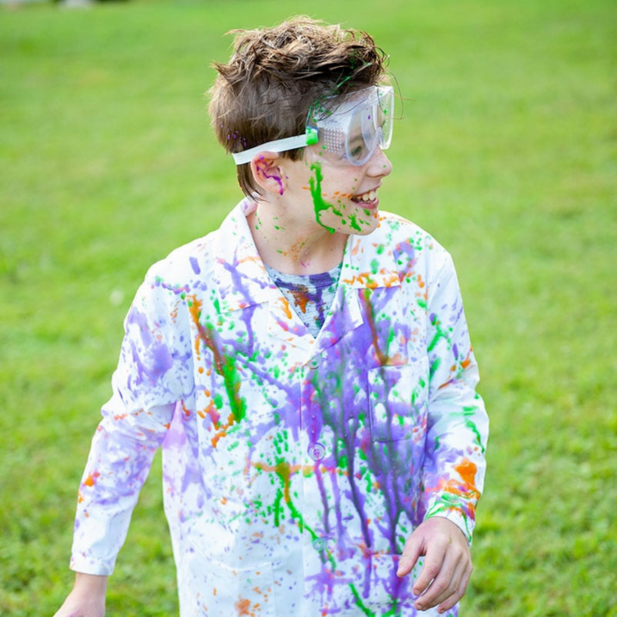 a boy playing outside covered in different coloured paints