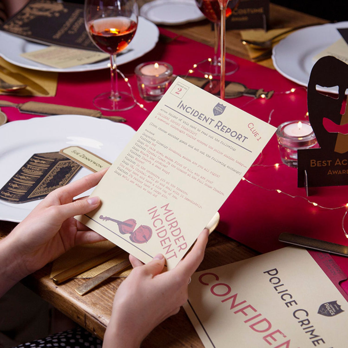 Person holding a 'Murder Incident' incident report card at a table with wine glasses and decor.