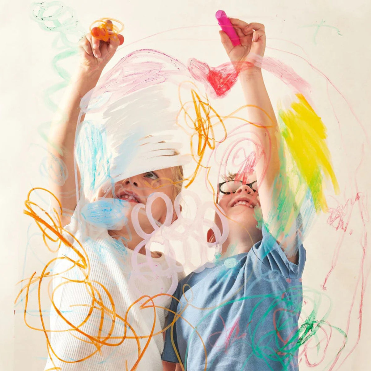 Two children using the paint sticks on a window highlighting its versatility beyond standard paper.