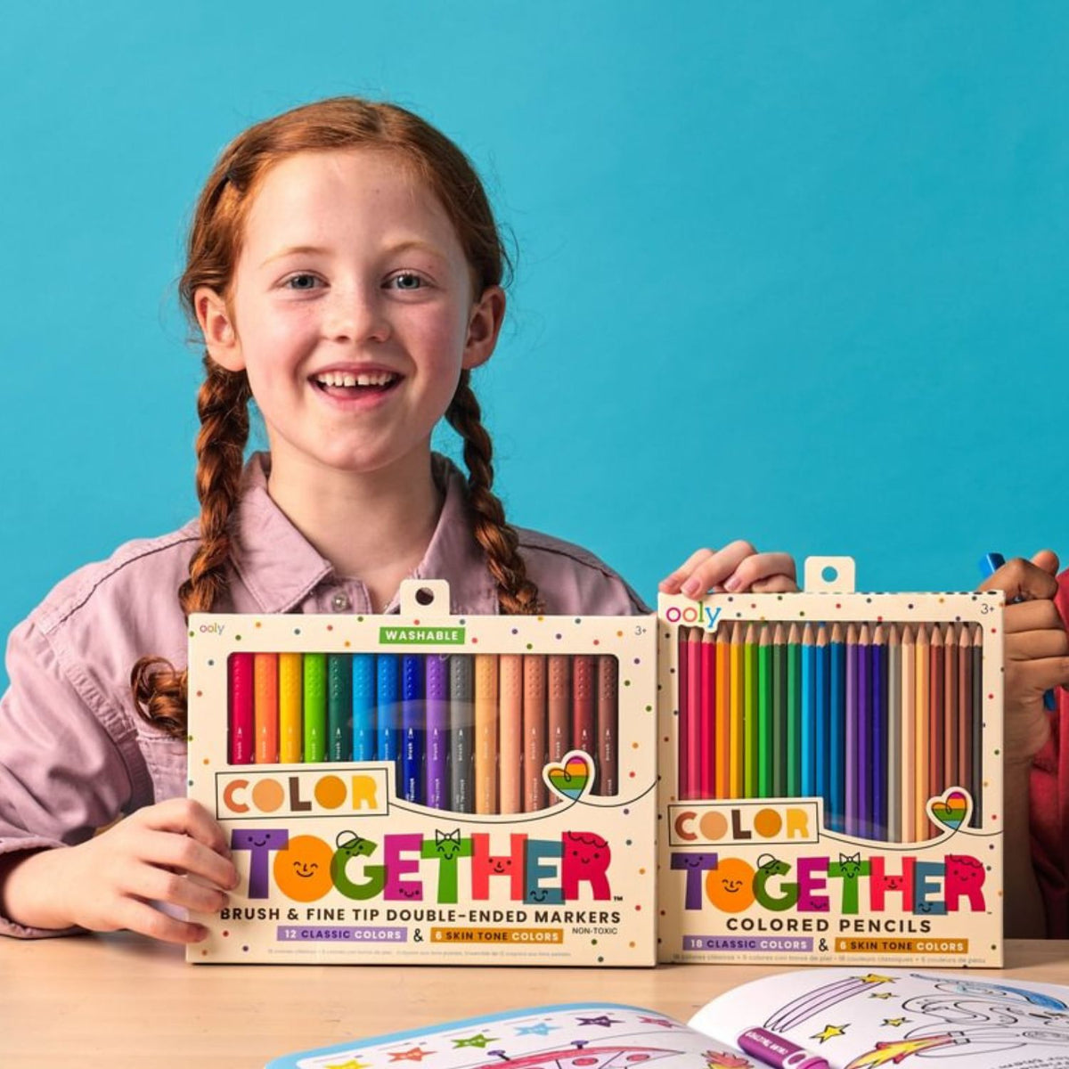 Girl holding 'Color Together' art supplies against a blue background