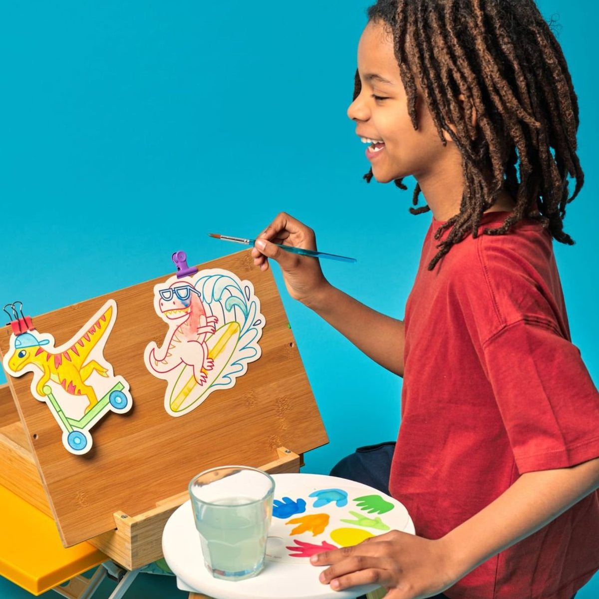 Child painting with colourful dinosaur watercolour cards 