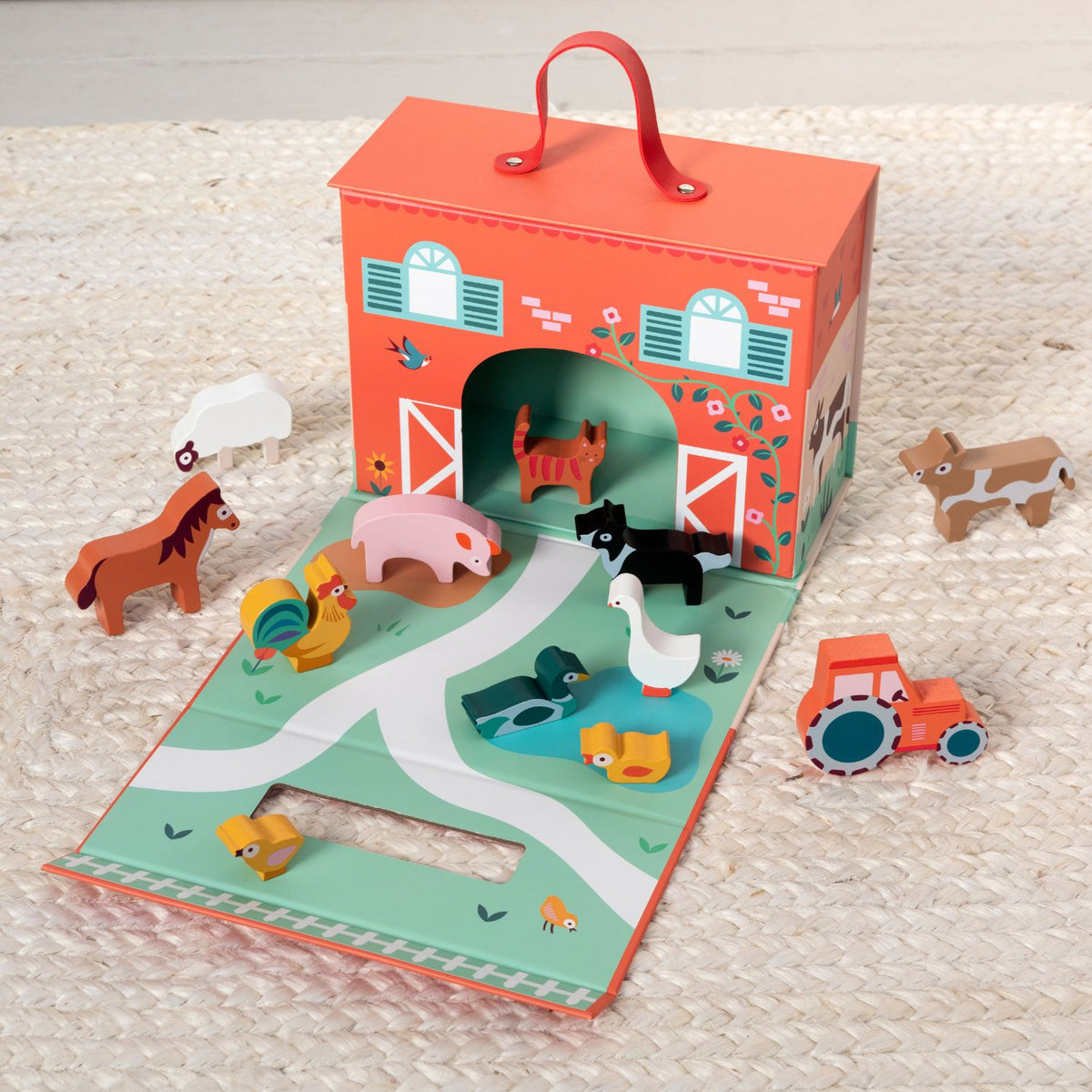 Children's toy set with a barn-shaped book and farm animal figures on a textured surface.